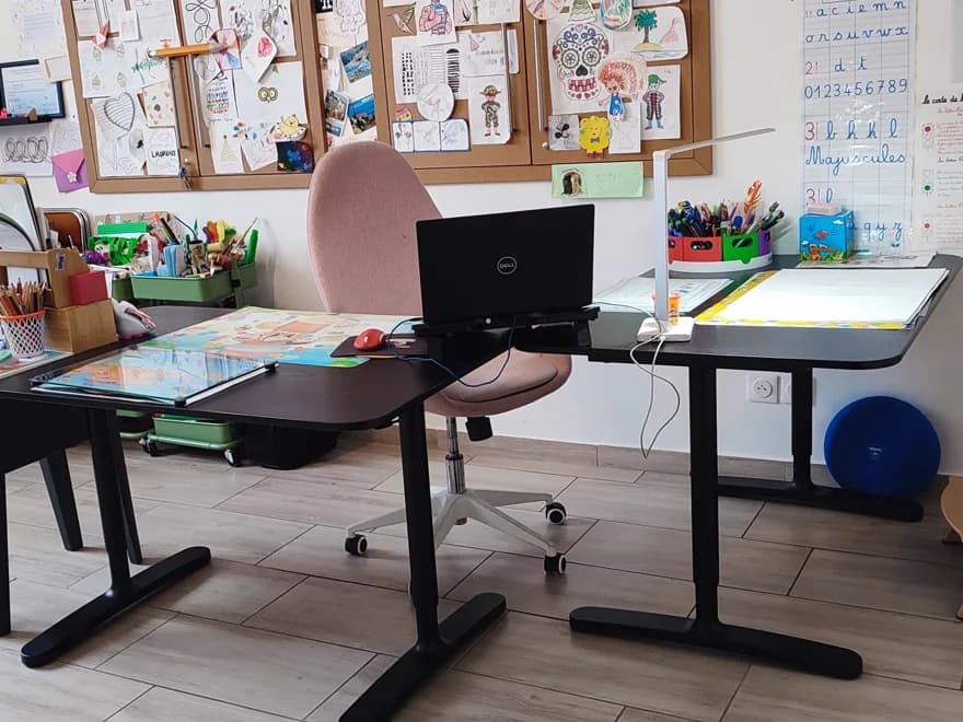L’espace des séances : deux bureaux, un fauteuil rose, des panneaux de liège couverts de dessins d’enfants et un alphabet cursif au mur.