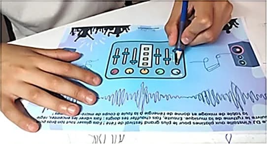 Main d’enfant tenant un crayon triangulaire à grip ergonomique sur une fiche « table de mixage », l’autre main posée à plat.