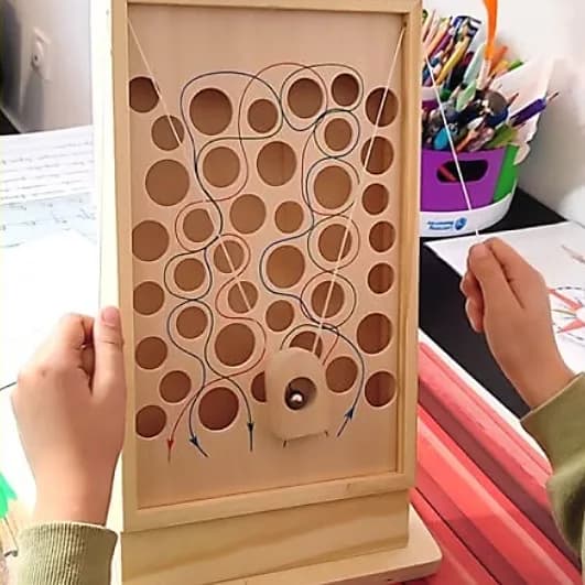 Labyrinthe en bois à trous, une bille guidée par deux ficelles que tiennent les mains de l’enfant.