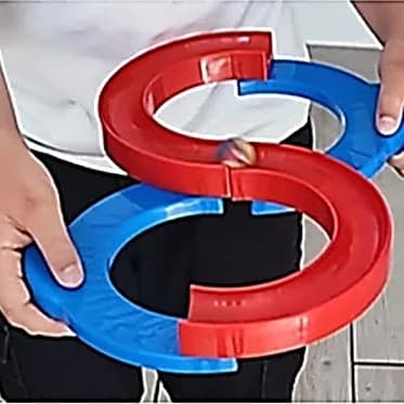 Mains d’enfant tenant une piste en S rouge et bleue où roule une bille.