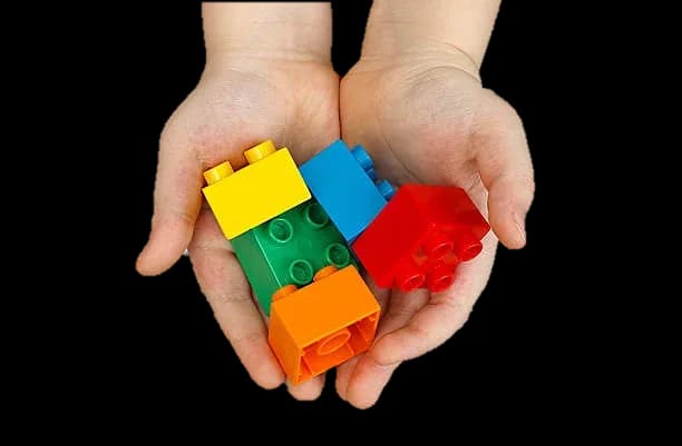 Quatre briques DUPLO colorées dans les mains en coupe d'un enfant