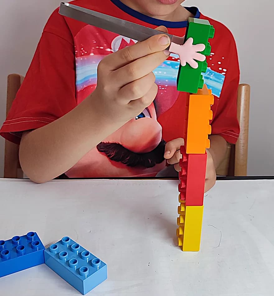 Un enfant fait tenir en équilibre une règle sur une tour de briques DUPLO® empilées